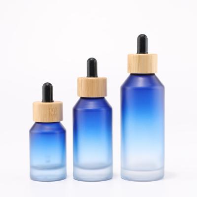 Flacon en verre bleu dégradé avec compte-gouttes en bambou pour emballage cosmétique
